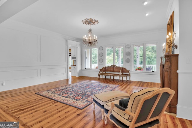 living area featuring ornamental molding, light wood-type flooring, and a chandelier