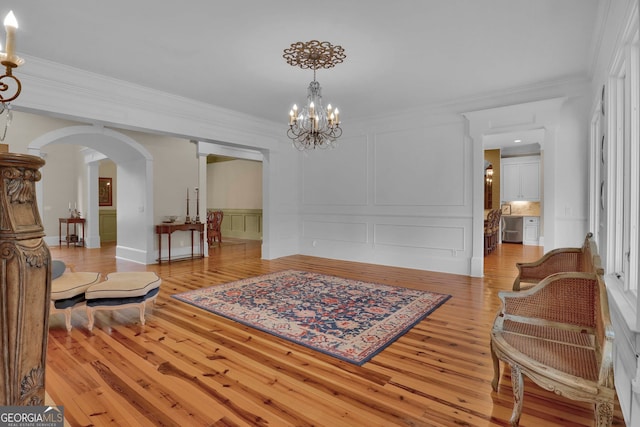 living area featuring ornamental molding, light hardwood / wood-style flooring, and an inviting chandelier