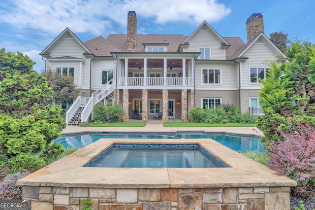 back of property with a pool with hot tub