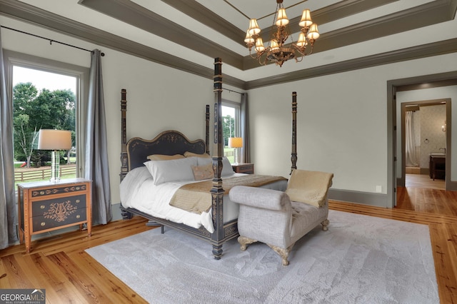 bedroom featuring light hardwood / wood-style flooring, ornamental molding, and a tray ceiling