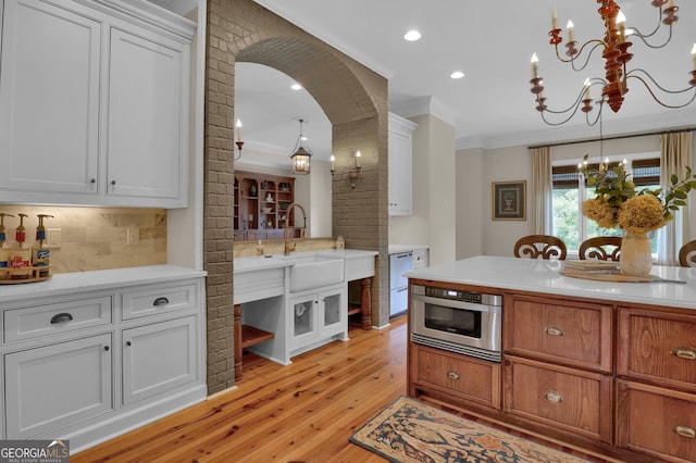 kitchen with appliances with stainless steel finishes, light hardwood / wood-style flooring, white cabinets, and decorative backsplash