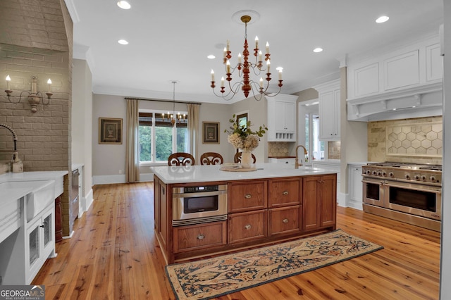 kitchen featuring a kitchen island with sink, light wood-type flooring, tasteful backsplash, and stainless steel appliances