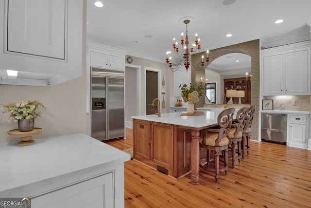 kitchen with light hardwood / wood-style floors, appliances with stainless steel finishes, white cabinetry, and a center island