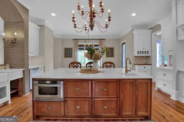 kitchen featuring stainless steel oven, light hardwood / wood-style flooring, sink, and a center island with sink