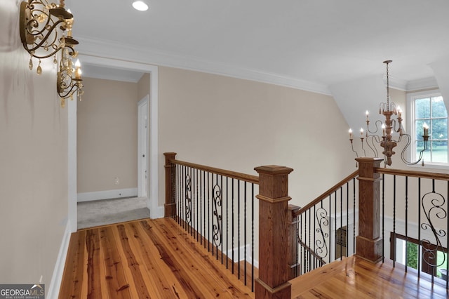 corridor with an inviting chandelier, crown molding, and hardwood / wood-style flooring