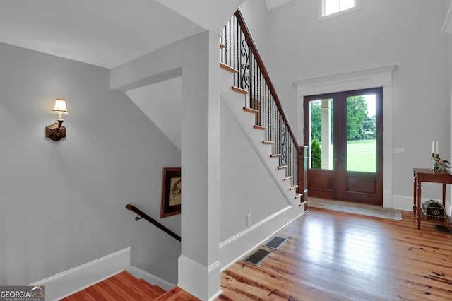 foyer entrance with a towering ceiling, french doors, and hardwood / wood-style floors