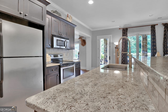 kitchen featuring dark brown cabinets, tasteful backsplash, light stone counters, and stainless steel appliances