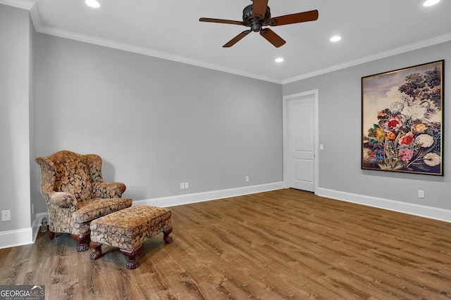 sitting room with hardwood / wood-style flooring, crown molding, and ceiling fan