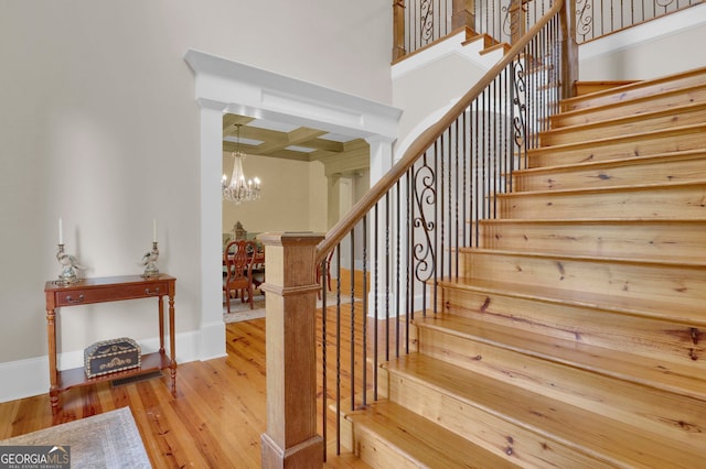 stairs featuring decorative columns, hardwood / wood-style flooring, and a chandelier