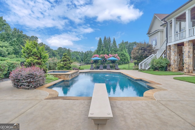 view of swimming pool featuring an in ground hot tub and a diving board