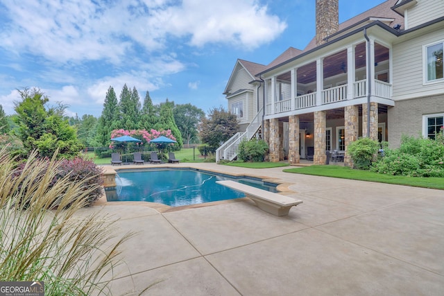 view of pool with a patio area, pool water feature, and a diving board