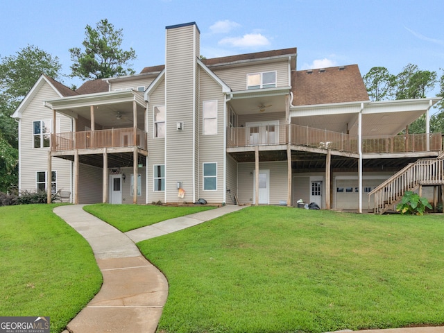 rear view of house featuring a garage, a balcony, ceiling fan, and a lawn