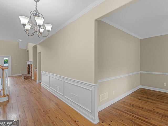 hall with wood-type flooring, crown molding, a notable chandelier, and visible vents