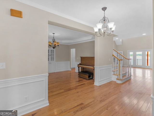 interior space featuring an inviting chandelier, light wood-type flooring, a decorative wall, and stairs