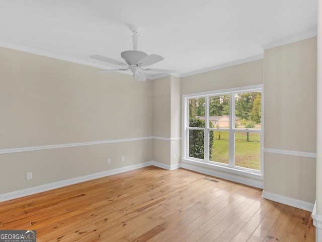spare room featuring a ceiling fan, baseboards, ornamental molding, and light wood-style floors