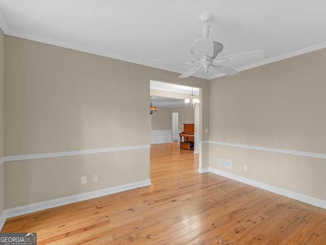 empty room with crown molding, wood-type flooring, and ceiling fan with notable chandelier