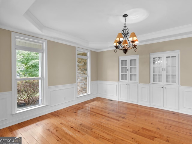 unfurnished dining area featuring a notable chandelier, crown molding, and light hardwood / wood-style floors