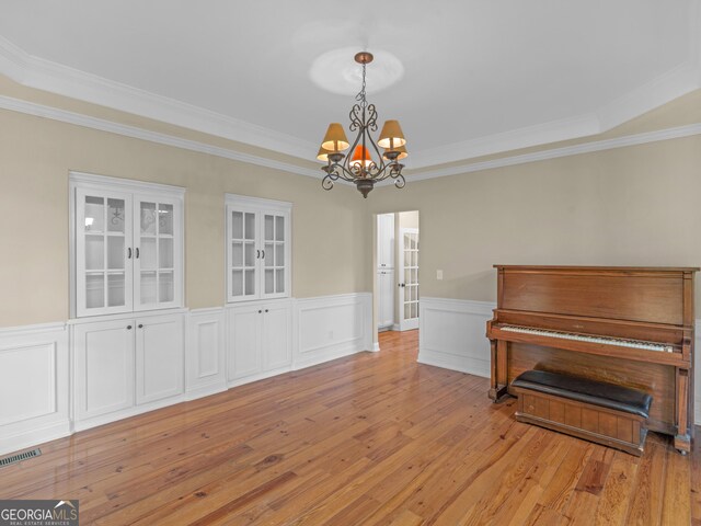 misc room featuring an inviting chandelier, ornamental molding, and light wood-type flooring