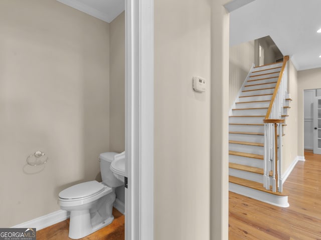 bathroom with crown molding, wood finished floors, baseboards, toilet, and recessed lighting