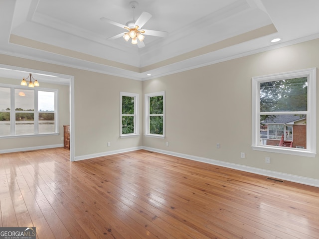 spare room featuring visible vents, crown molding, a tray ceiling, and light wood-type flooring