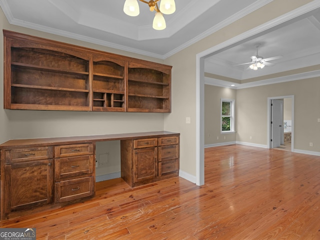 bar with crown molding, light hardwood / wood-style flooring, ceiling fan, a tray ceiling, and built in desk