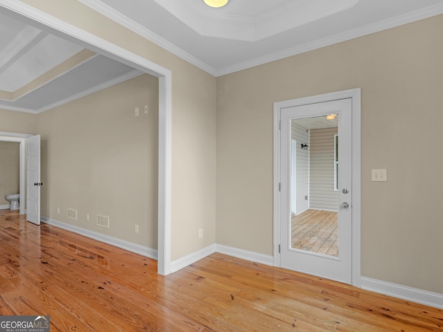 empty room with baseboards, visible vents, ornamental molding, and light wood-style floors