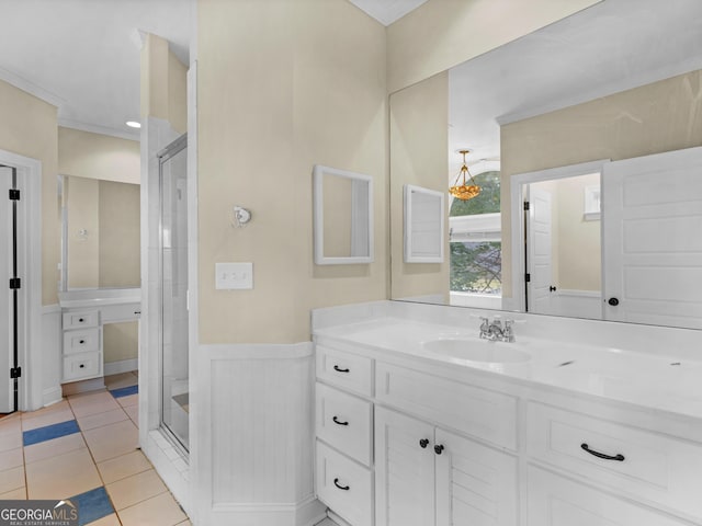 full bath with wainscoting, vanity, tile patterned floors, a shower stall, and ornamental molding