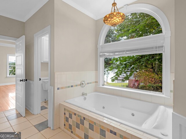 bathroom with a relaxing tiled tub, crown molding, tile patterned floors, and a healthy amount of sunlight