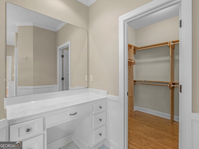 bathroom with vanity, ornamental molding, baseboards, and wood finished floors