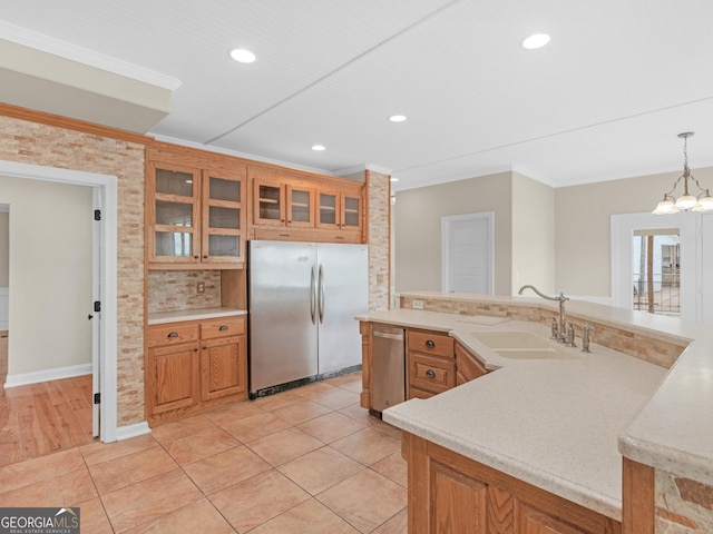 kitchen featuring appliances with stainless steel finishes, sink, hanging light fixtures, ornamental molding, and an inviting chandelier