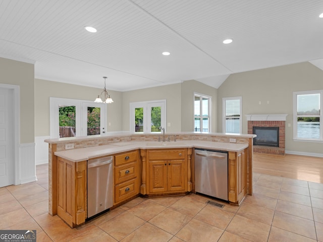 kitchen featuring stainless steel dishwasher, decorative light fixtures, sink, and a center island with sink