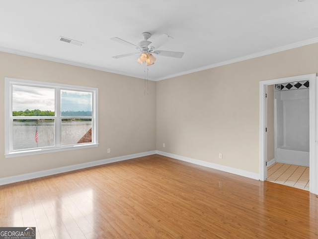empty room with crown molding, ceiling fan, baseboards, light wood-type flooring, and visible vents