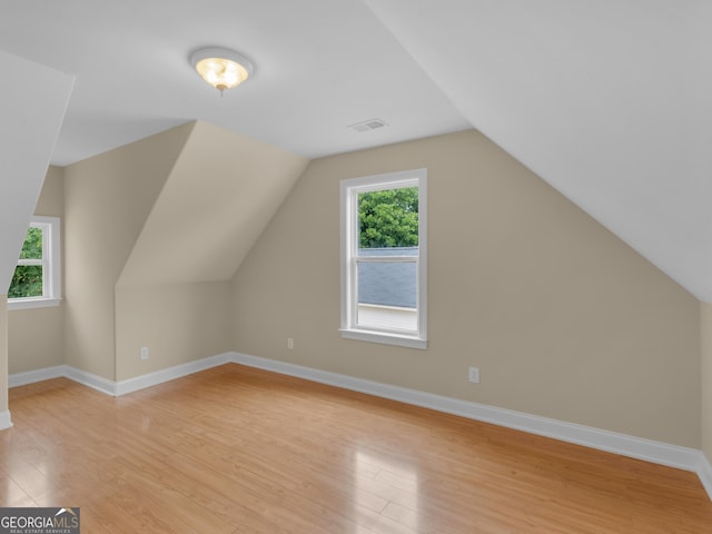 additional living space featuring baseboards, visible vents, lofted ceiling, and light wood-style floors