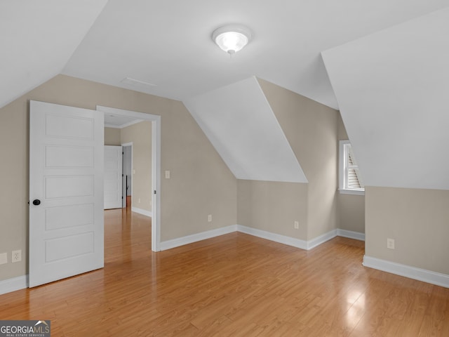 bonus room with baseboards, light wood-style flooring, and vaulted ceiling