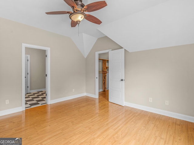 interior space featuring baseboards, light wood-type flooring, and lofted ceiling