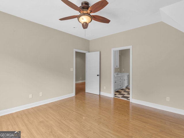 unfurnished bedroom with baseboards, light wood finished floors, ceiling fan, and ensuite bath
