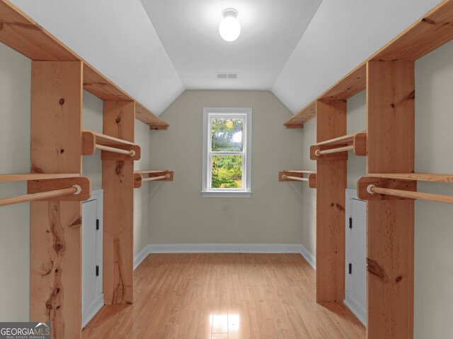 walk in closet with lofted ceiling, light wood-type flooring, and visible vents