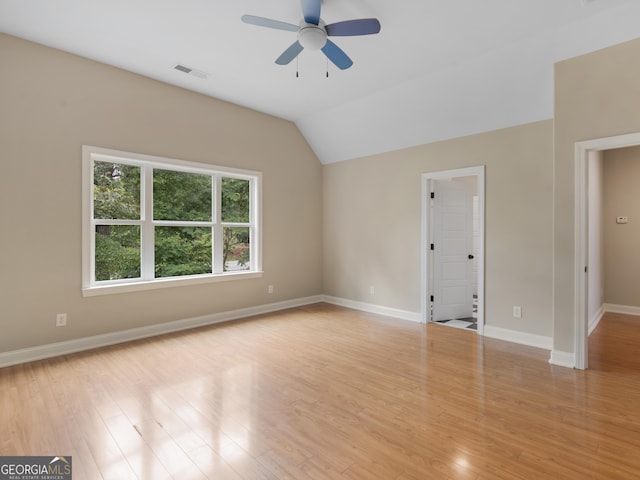 empty room featuring visible vents, light wood-style floors, baseboards, a ceiling fan, and vaulted ceiling