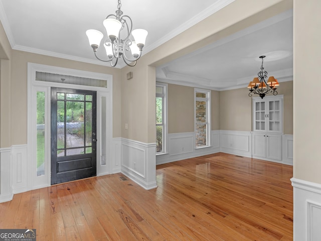 entryway featuring a notable chandelier, wainscoting, ornamental molding, and light wood finished floors