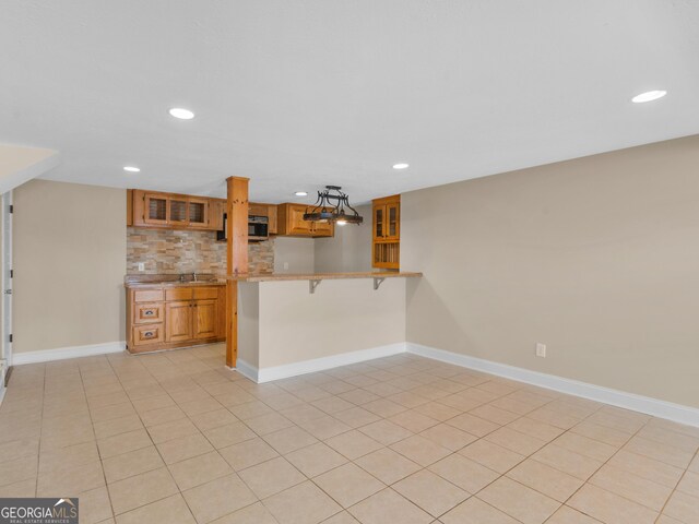 kitchen with tasteful backsplash, decorative light fixtures, light tile patterned floors, a kitchen breakfast bar, and kitchen peninsula