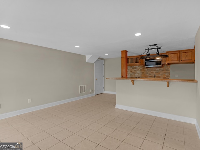 kitchen featuring a breakfast bar area, decorative backsplash, and kitchen peninsula