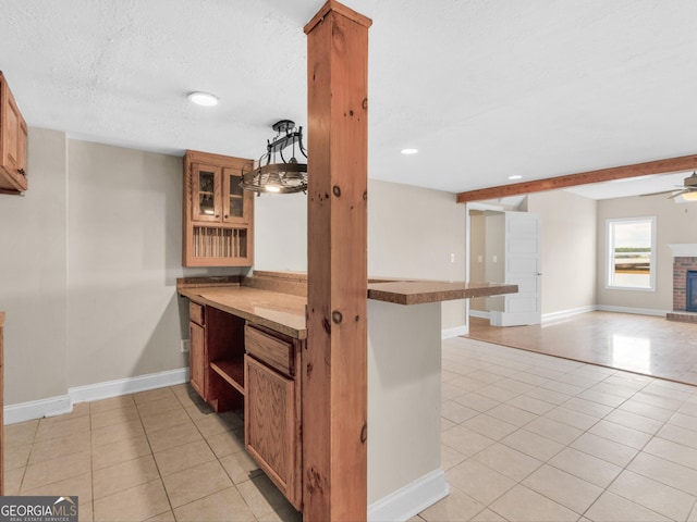 kitchen featuring light tile patterned flooring, pendant lighting, a fireplace, ceiling fan, and kitchen peninsula