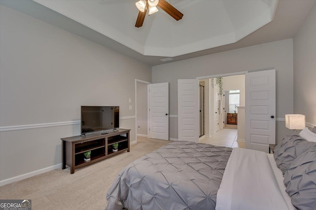 carpeted bedroom with ceiling fan and a raised ceiling