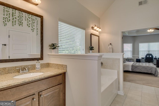 bathroom with tile patterned flooring, vanity, lofted ceiling, and a bath