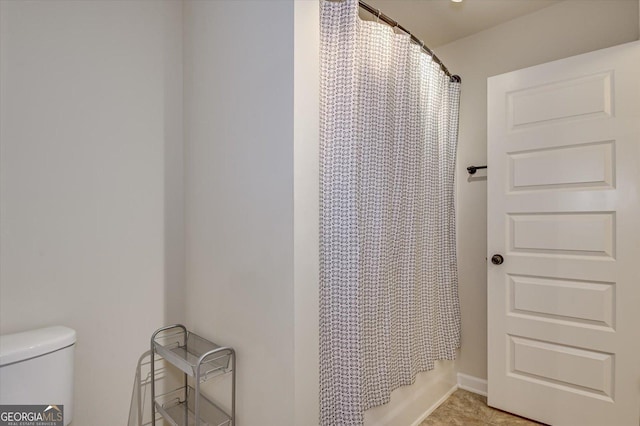 bathroom featuring shower / tub combo and toilet