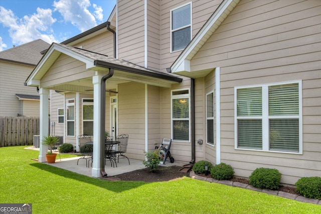 property entrance featuring cooling unit, a lawn, and a patio area