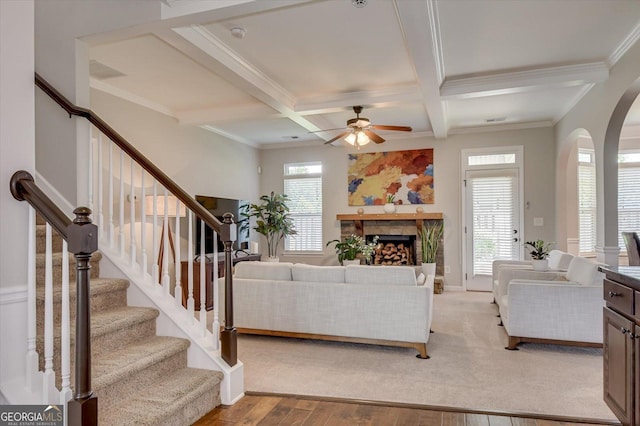 living room with coffered ceiling, crown molding, light wood-type flooring, ceiling fan, and beam ceiling