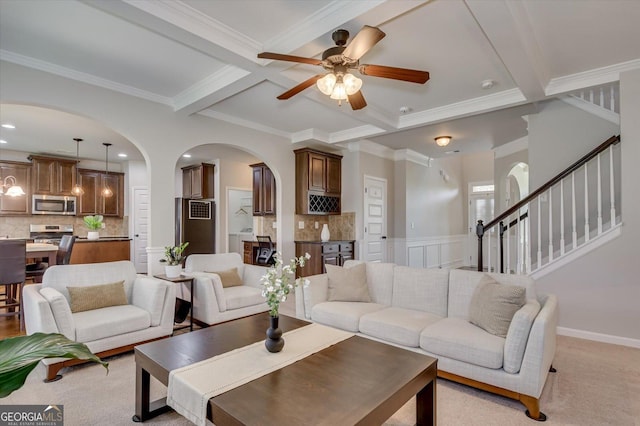 carpeted living room featuring coffered ceiling, beam ceiling, ornamental molding, and ceiling fan