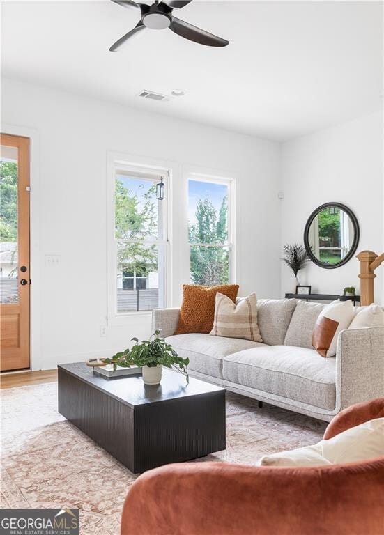 living area with visible vents, light wood-style floors, and a ceiling fan