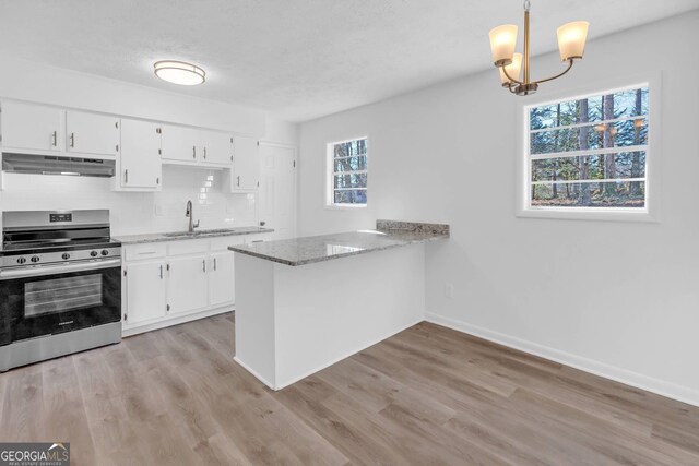 kitchen featuring stainless steel range oven, kitchen peninsula, light hardwood / wood-style flooring, and a wealth of natural light